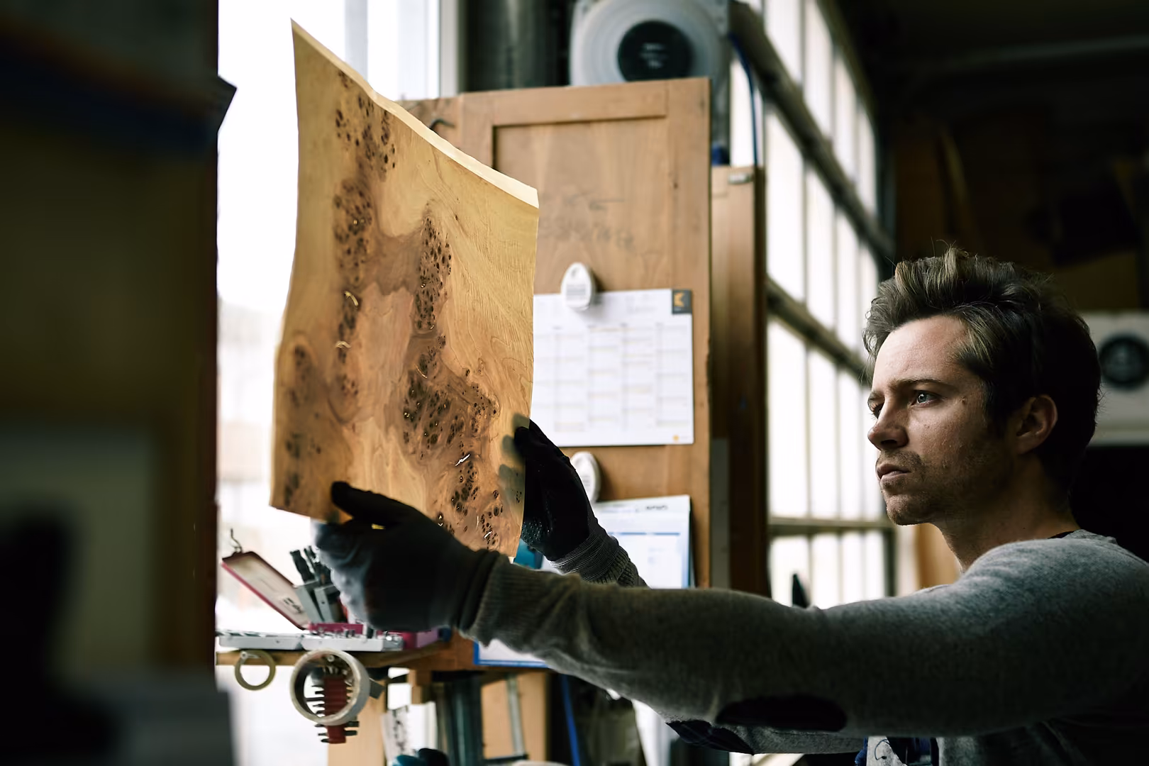 Matthias Stölzle, CEO von LeuchtNatur, prüft die Maserung eines Furnierholzes in der Werkstatt